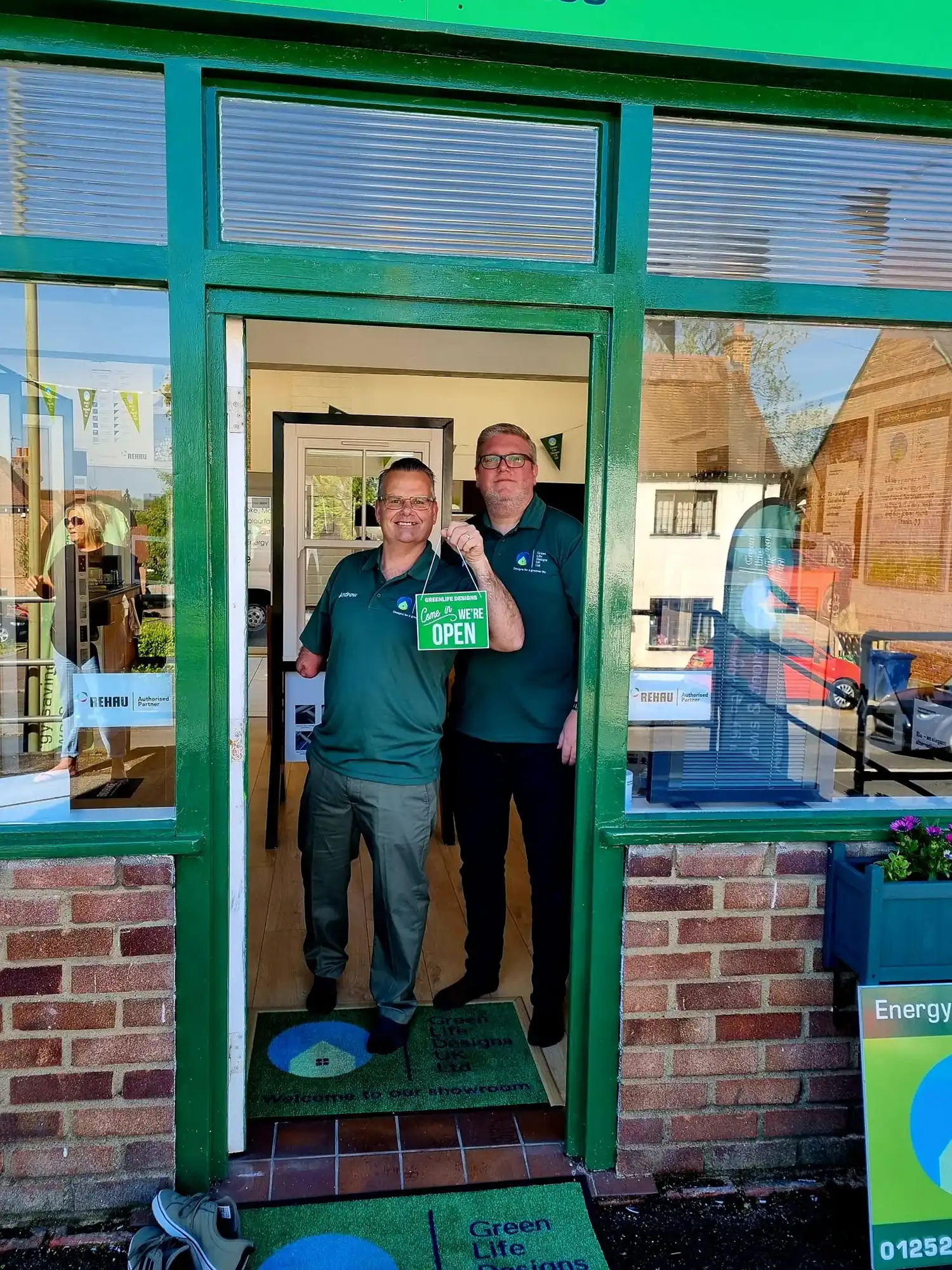 two men standing in a doorway of a store holding a sign